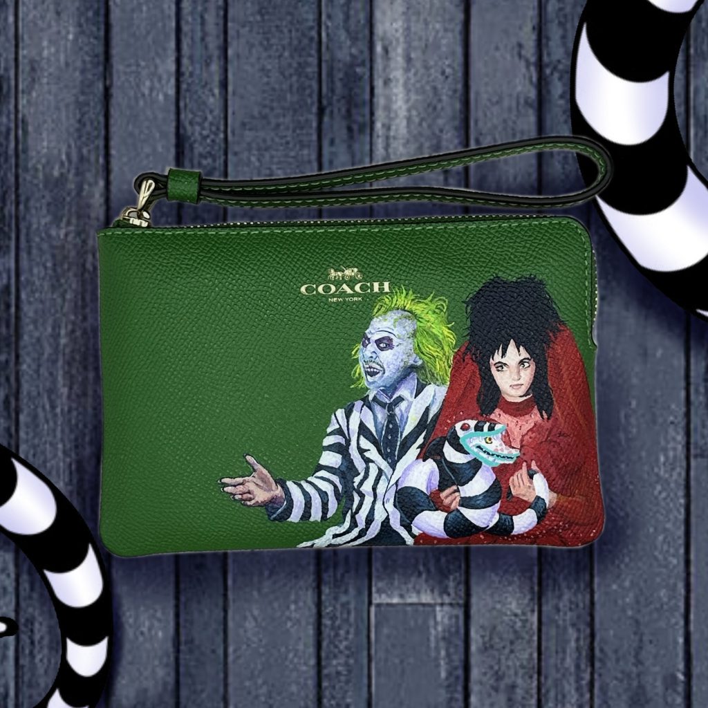 Green Coach wristlet with Beetlejuice and Lydia holding a sandworm